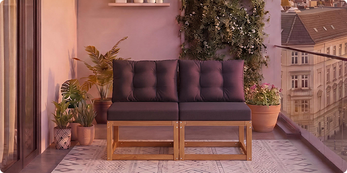 Kétüléses moduláris fa kanapé sötétszürke párnákkal erkélyen, cserepesvirágokkal körülvéve, háttérben városképpel