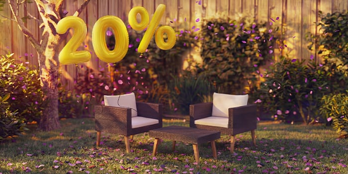  Kültéri rattan lounge fotelek párnákkal és egy kis asztallal kerti környezetben, rózsaszín konfettivel és arany „20% kedvezmény” feliratú lufikkal díszítve, kiemelve a kerti lounge bútorok szezonális ajánlatait.